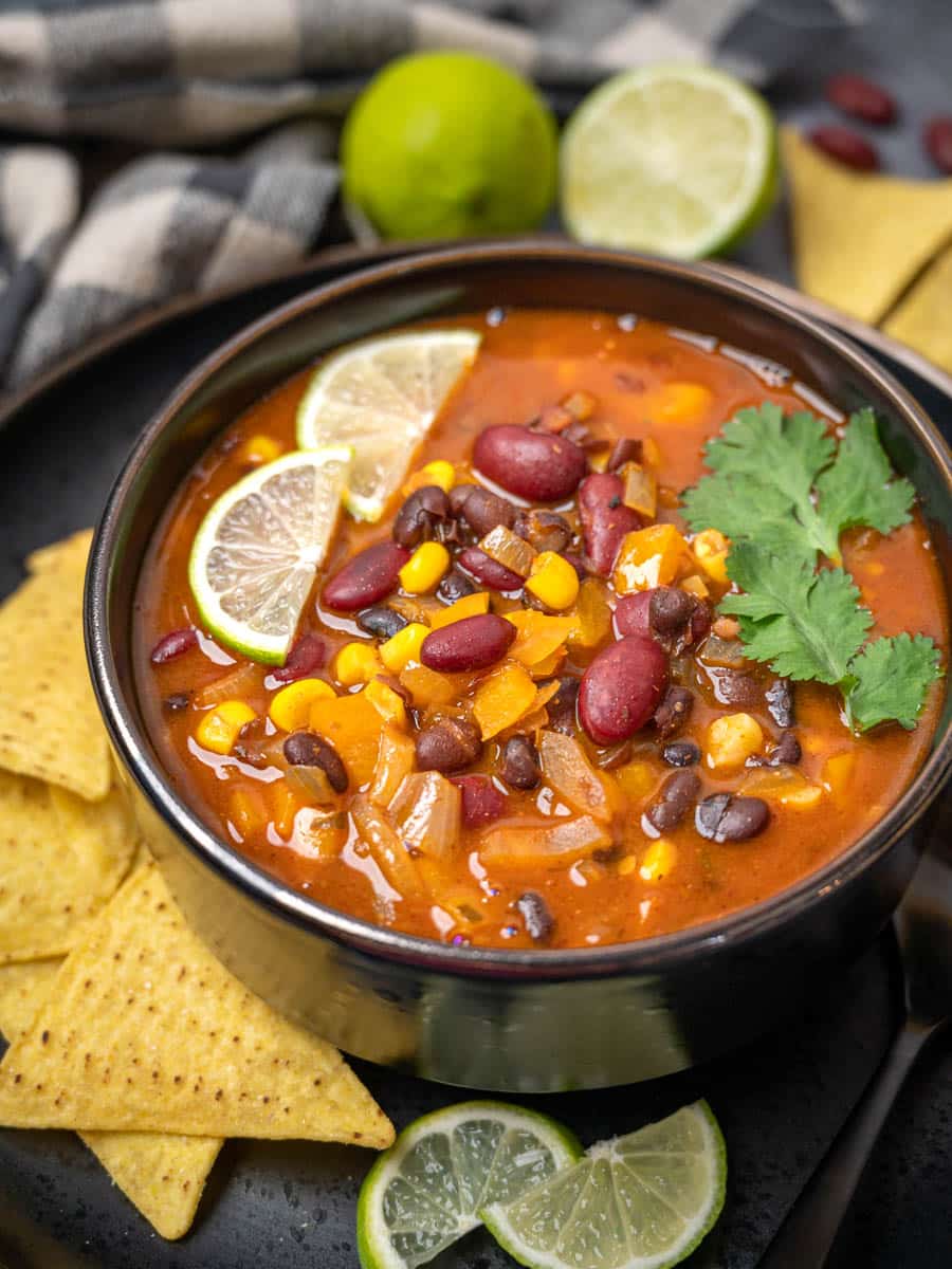 A bowl of beans soup with tortilla chips on the side